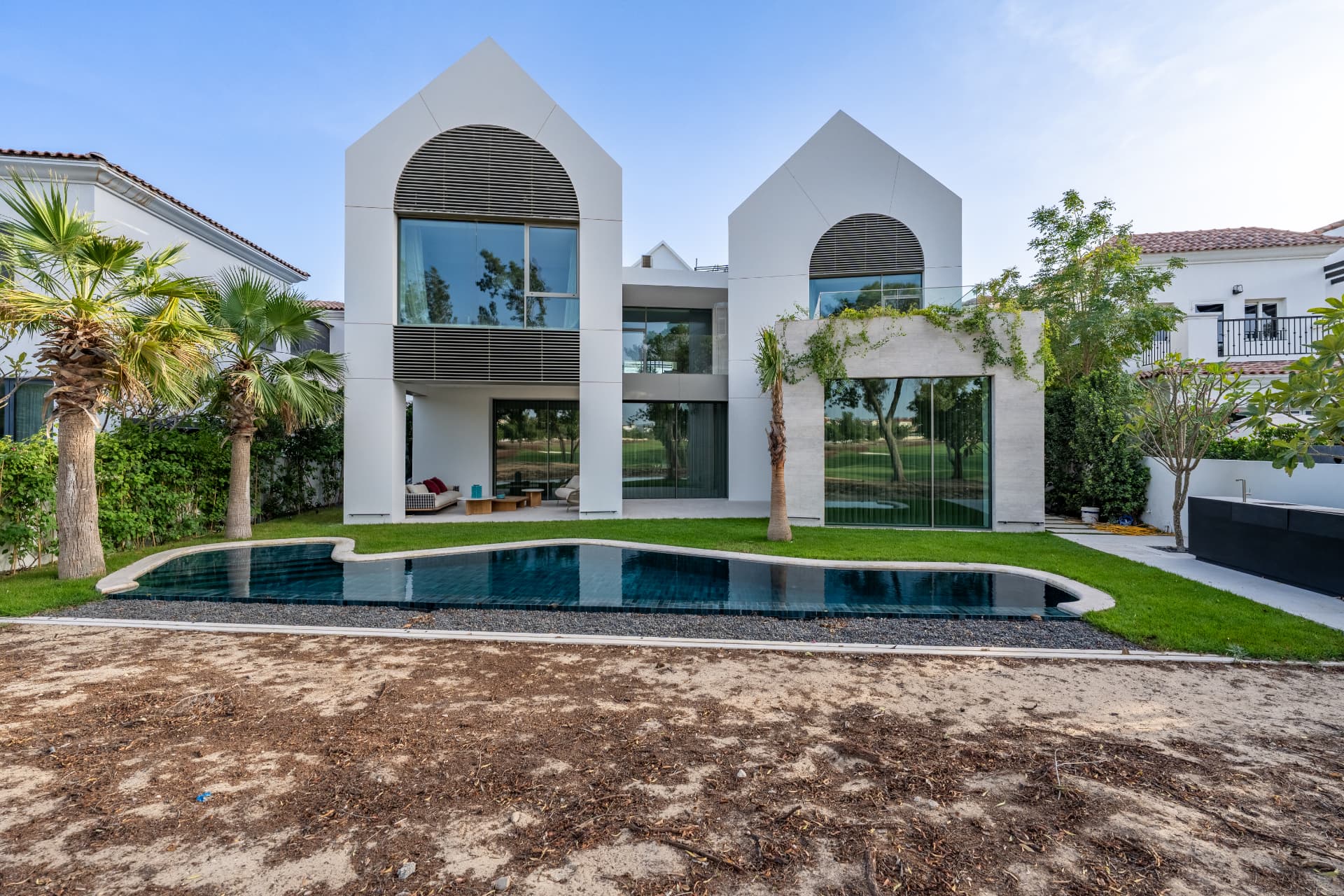 K82 rear elevation by day — two arched gable volumes above the curved pool and lawn