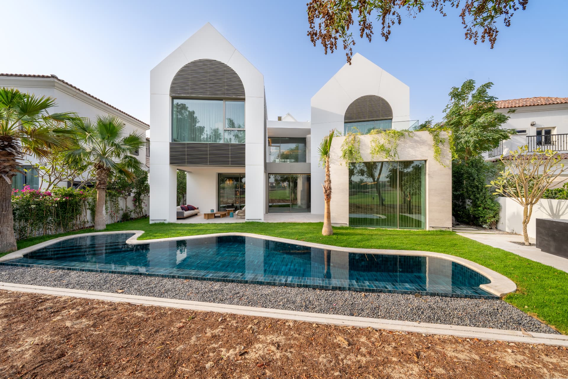K82 wide rear garden view with the curved pool, gravel border, lawn and planted boundary by day