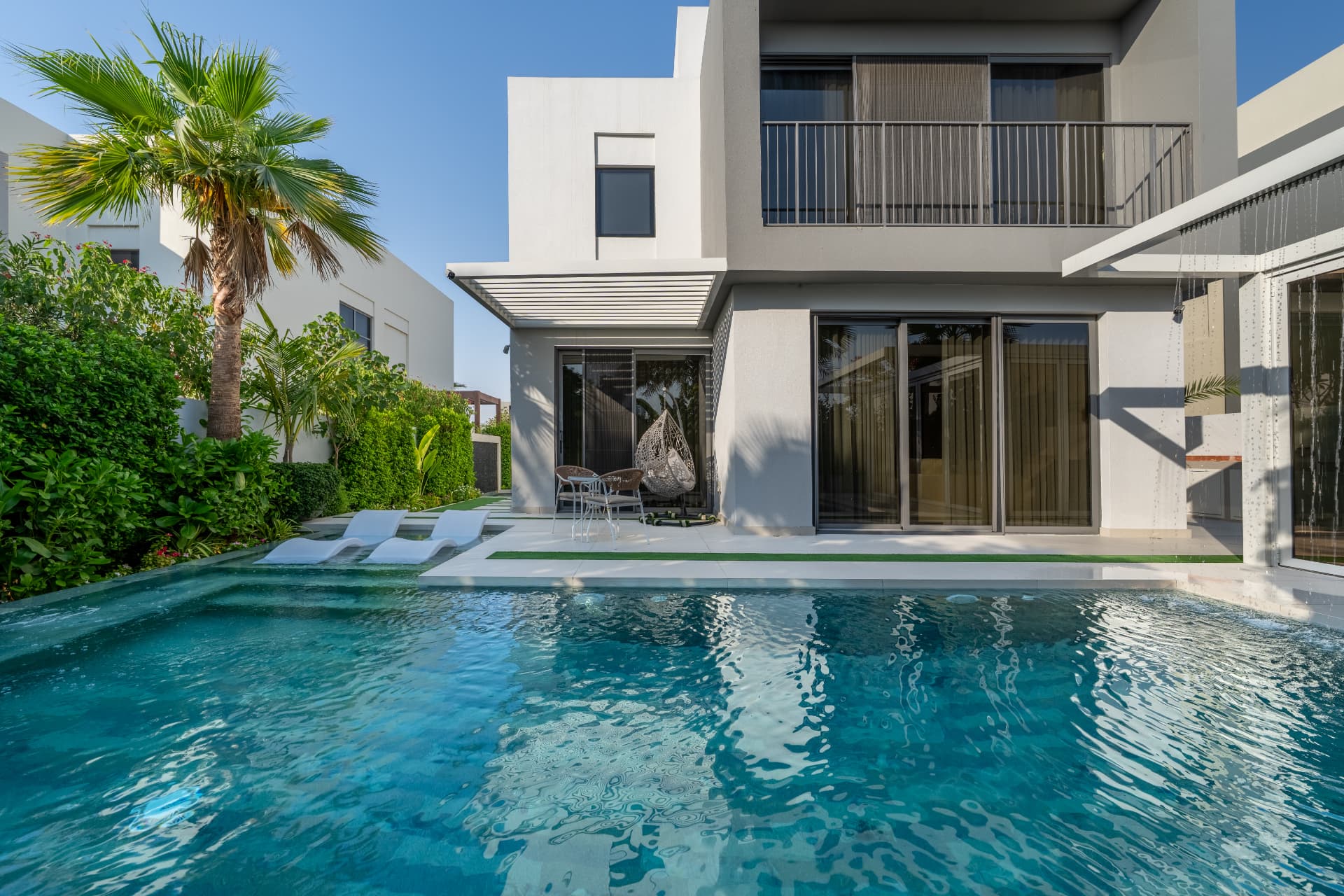 Villa 41 by day — pool with sun-shelf loungers in front of the white villa and louvred canopy