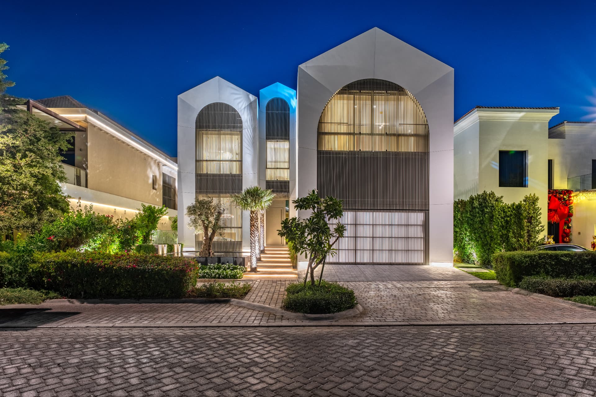 K47 street elevation at blue hour, gabled white volumes with fluted timber screens lit from within