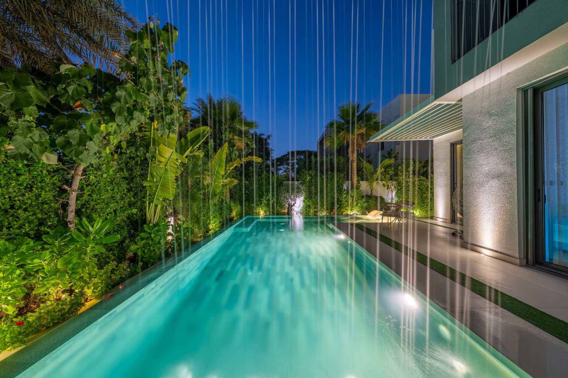 Villa 41 in Sidra 1 — bespoke rain-curtain water feature falling beside the illuminated lap pool
