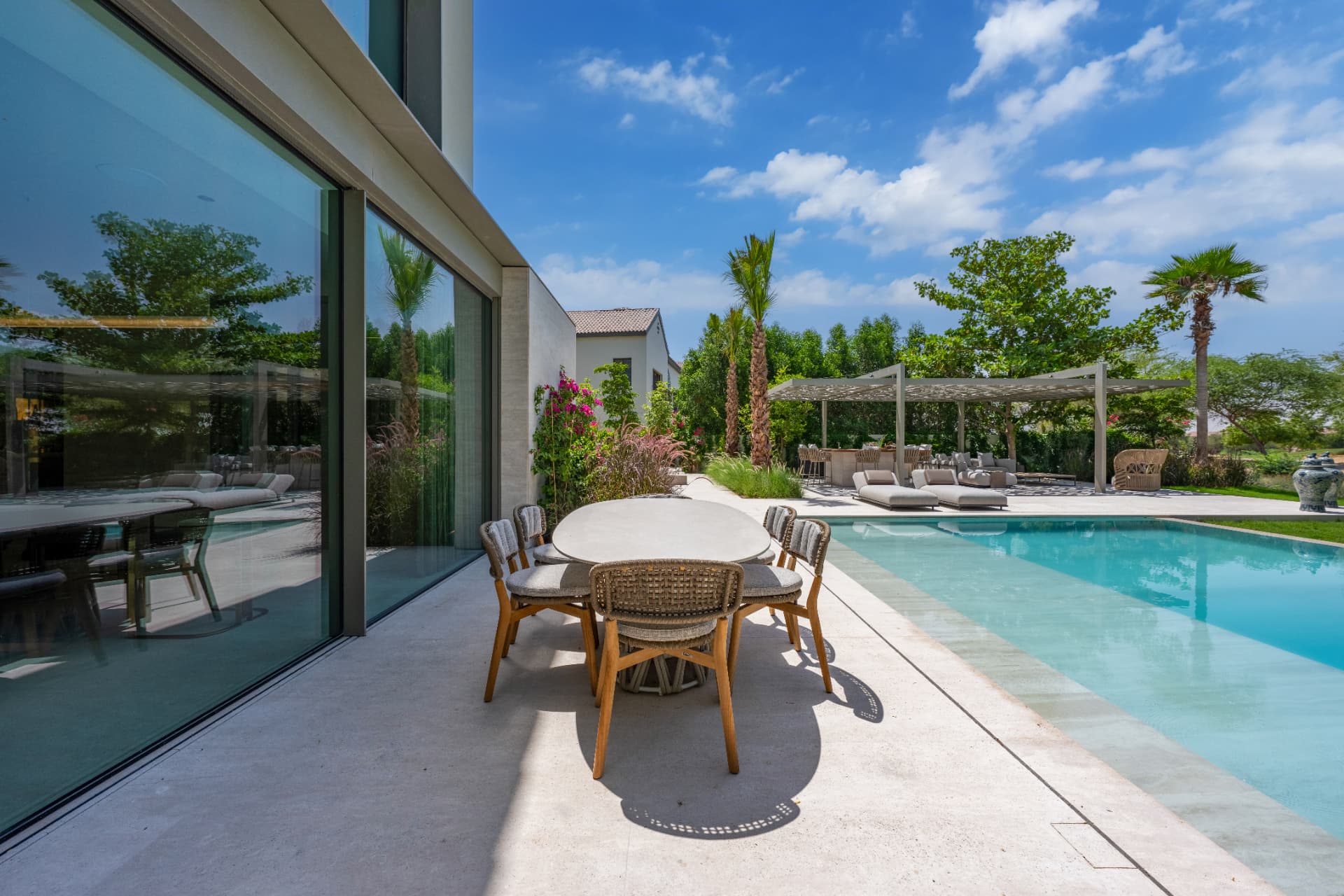 C51 — poolside eethoek naast de volglazen gevel met pergola en loungezone op de achtergrond