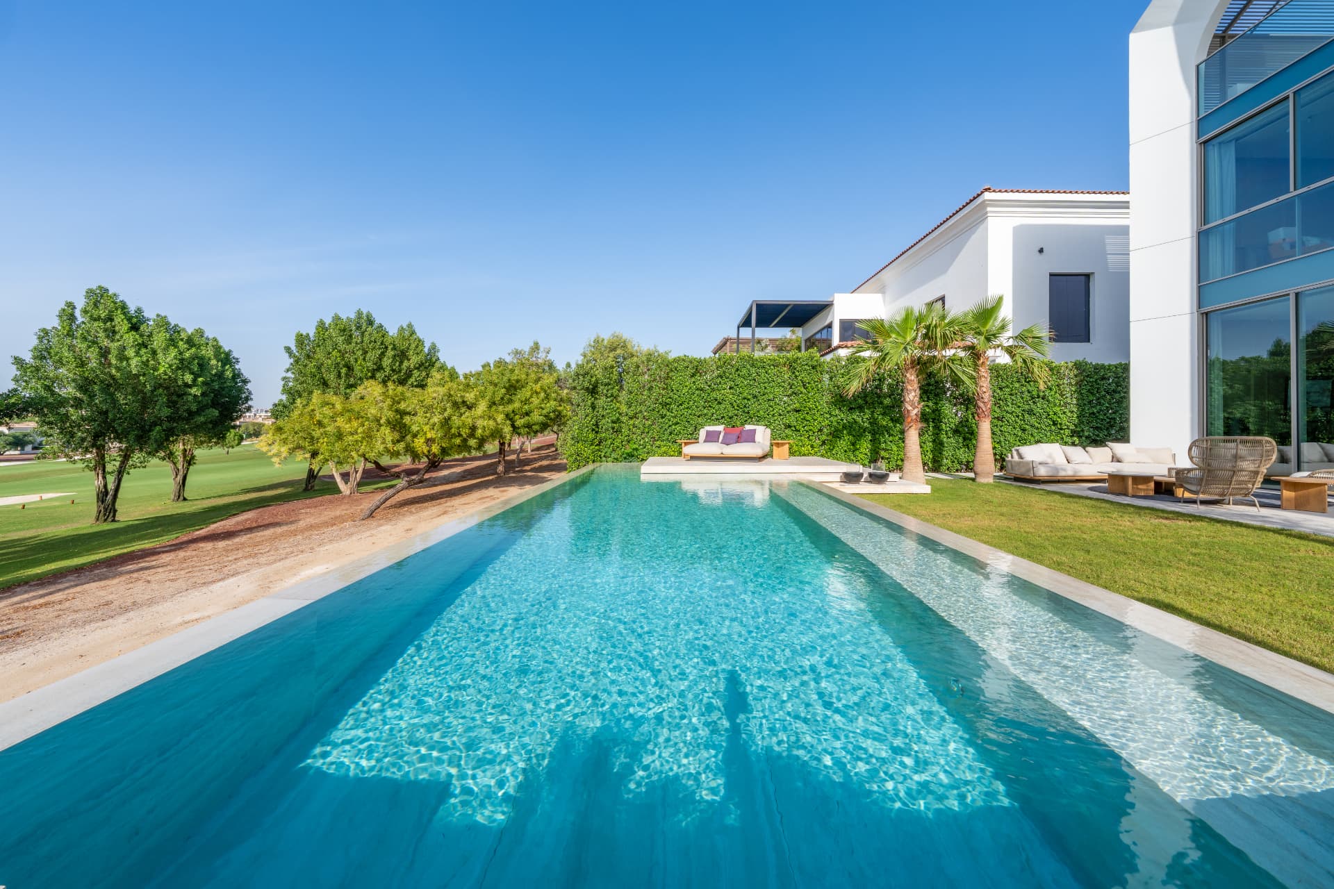 K47 lap pool running along the lawn towards the golf course, with daybed platform and clipped hedge