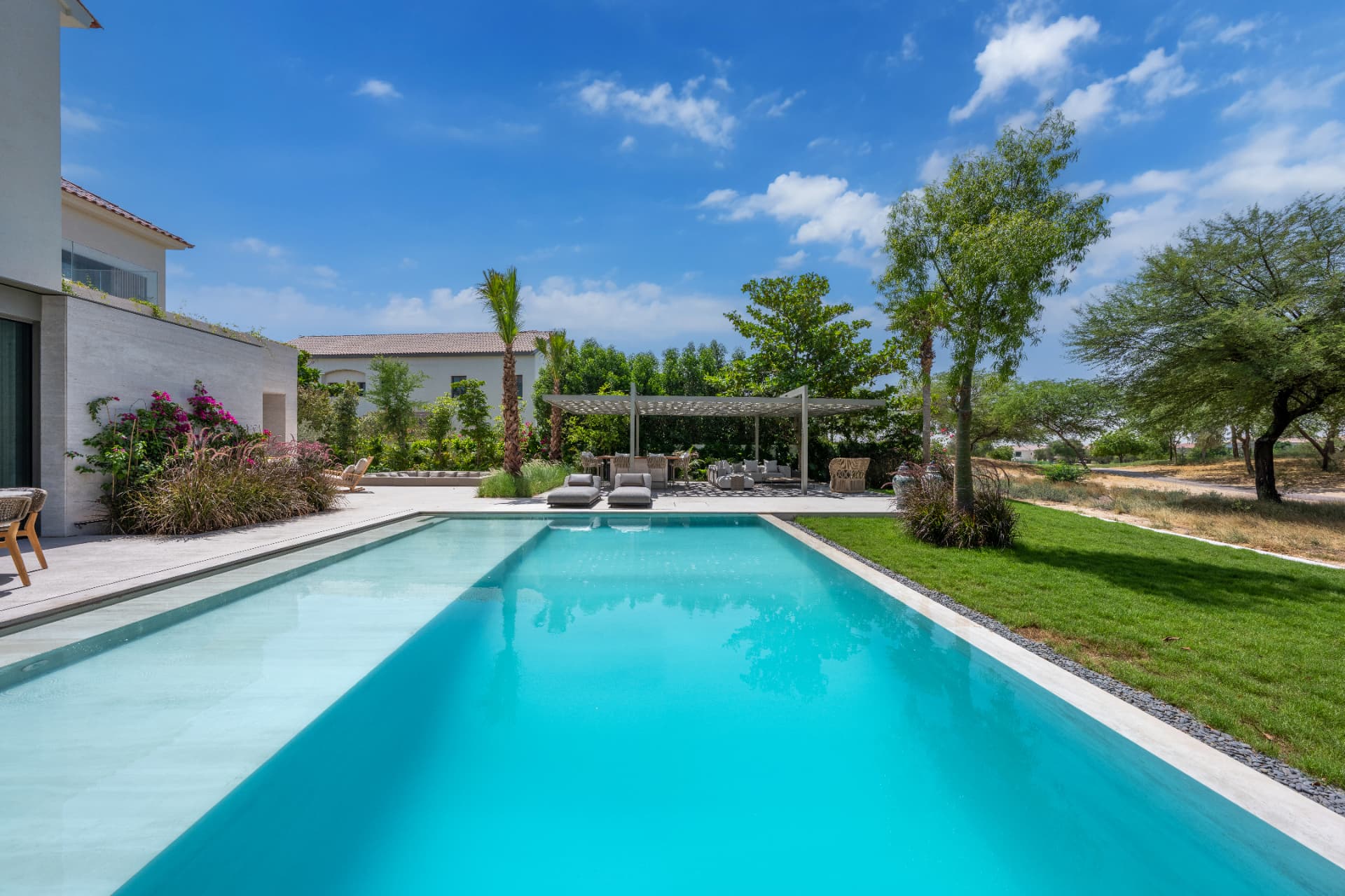 C51 — long lap pool alongside the travertine terrace, with pergola lounge and planted borders