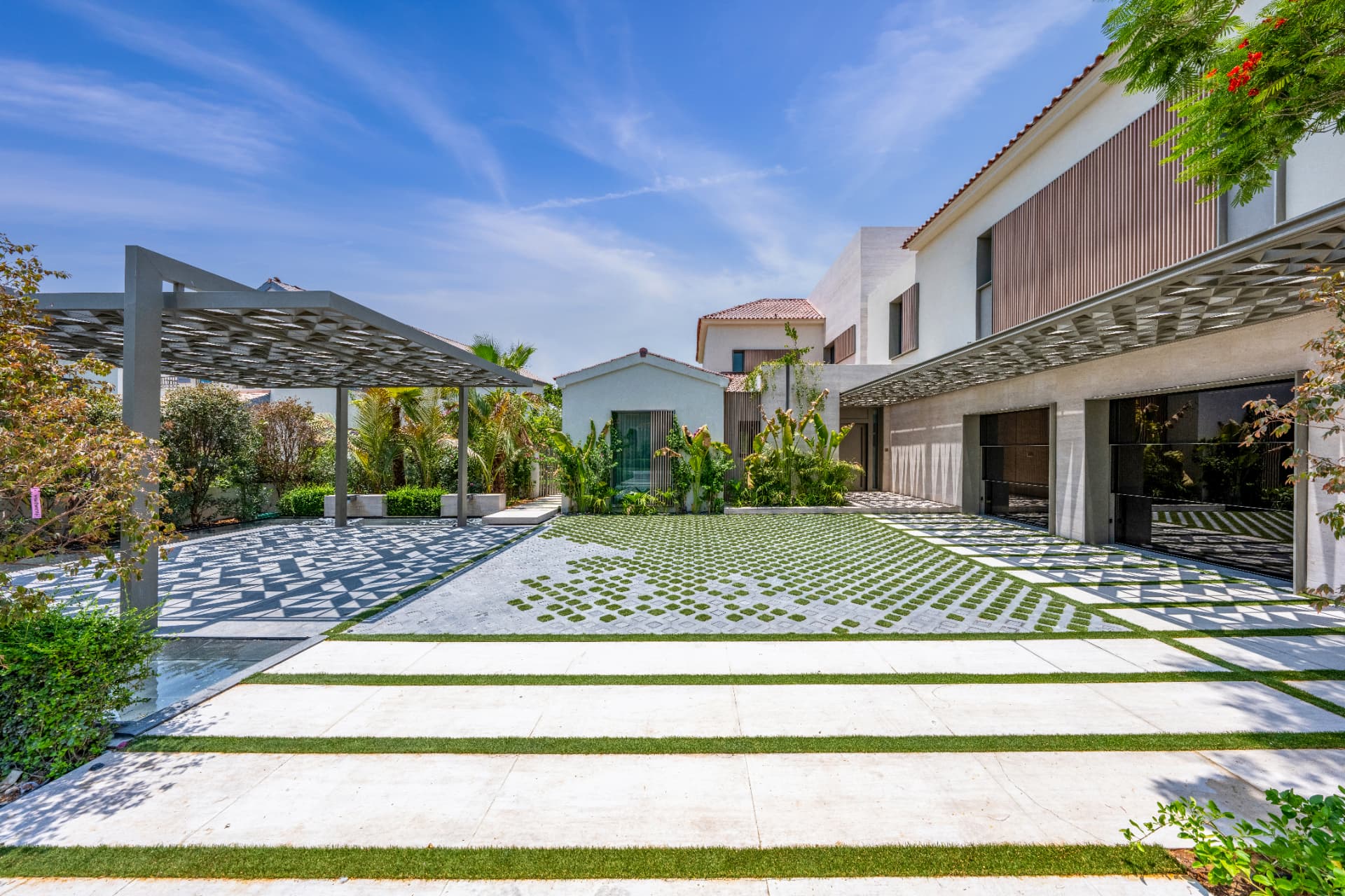 C51 — entrance court with grass-jointed paving, patterned stone inlays and latticed carport canopies