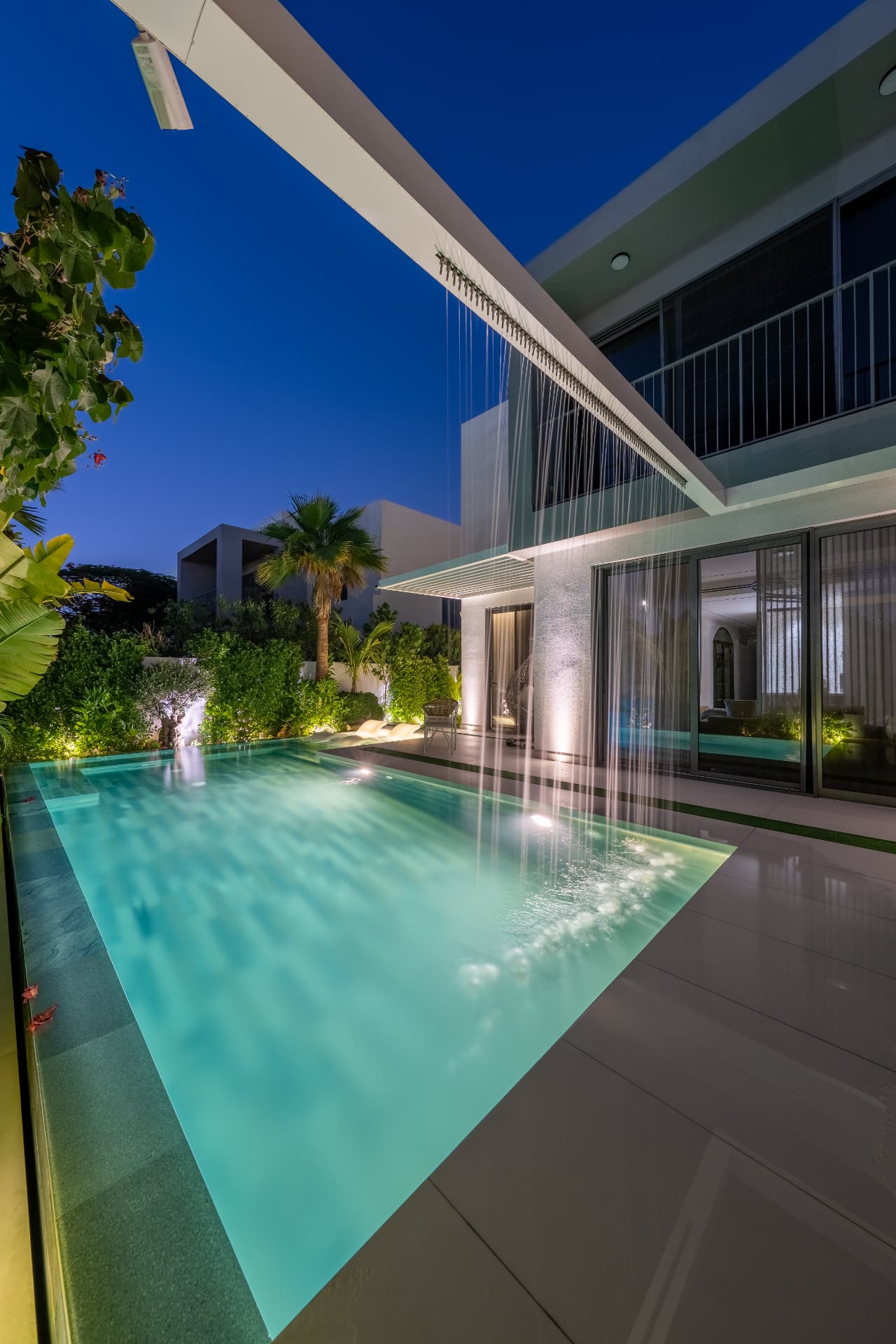 Villa 41 rain curtain falling from the pergola beam into the illuminated pool at night