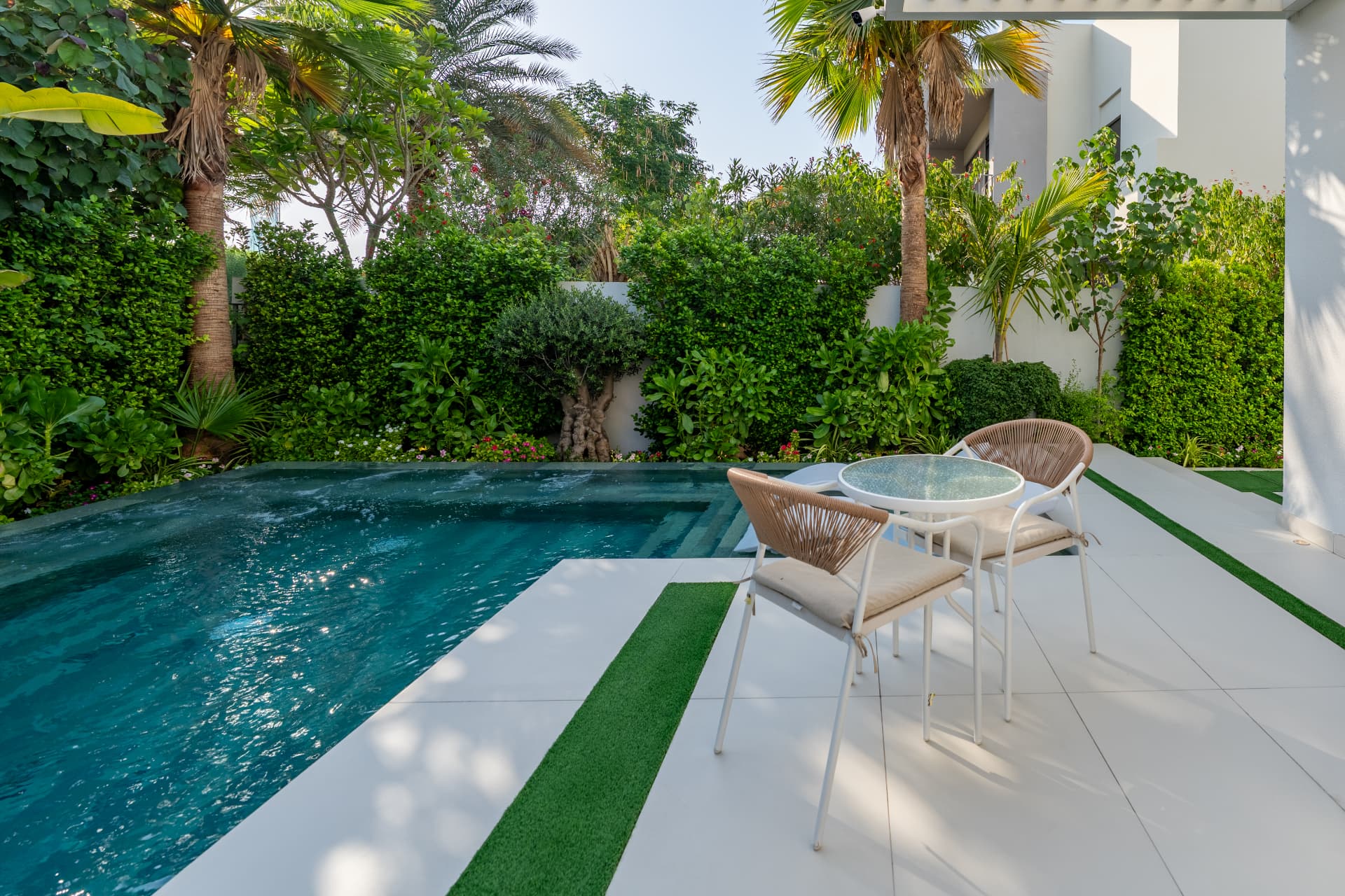 Villa 41 pool terrace by day with seating, striped lawn inlays and dense tropical planting