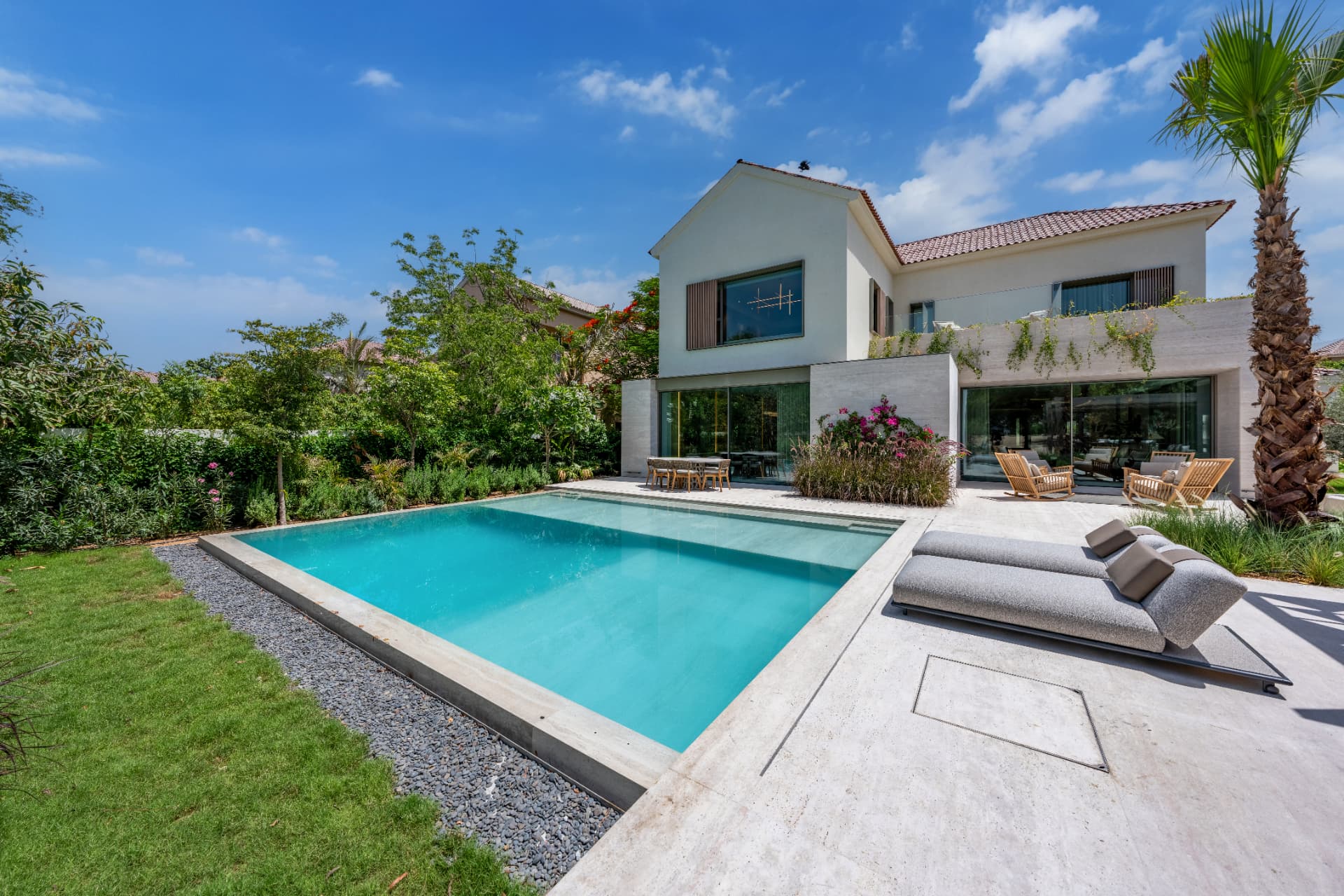 C51 — pool with stone coping and gravel edge, loungers on the terrace and the villa behind