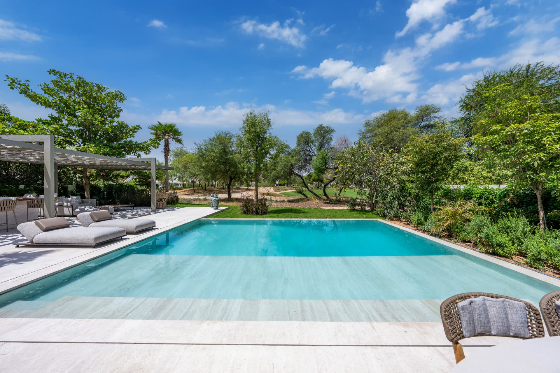 C51 — pool and terrace with sun loungers looking out over the golf course and mature trees